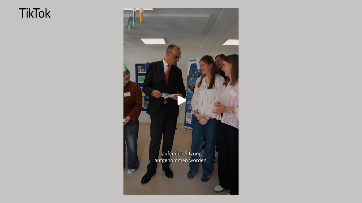 Bundeskanzler Merz im Gespräch mit Schülerinnen in einer Schule.