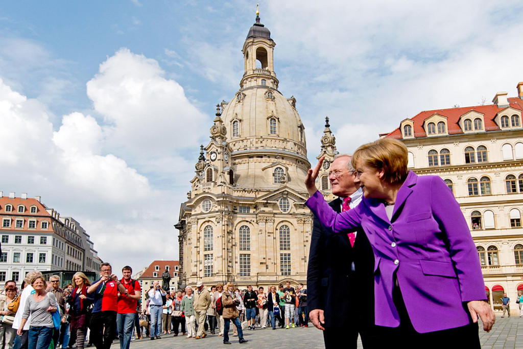Chancellor Angela Merkel waves to the crowds in Dresden; behind her the celebrated Frauenkirche.