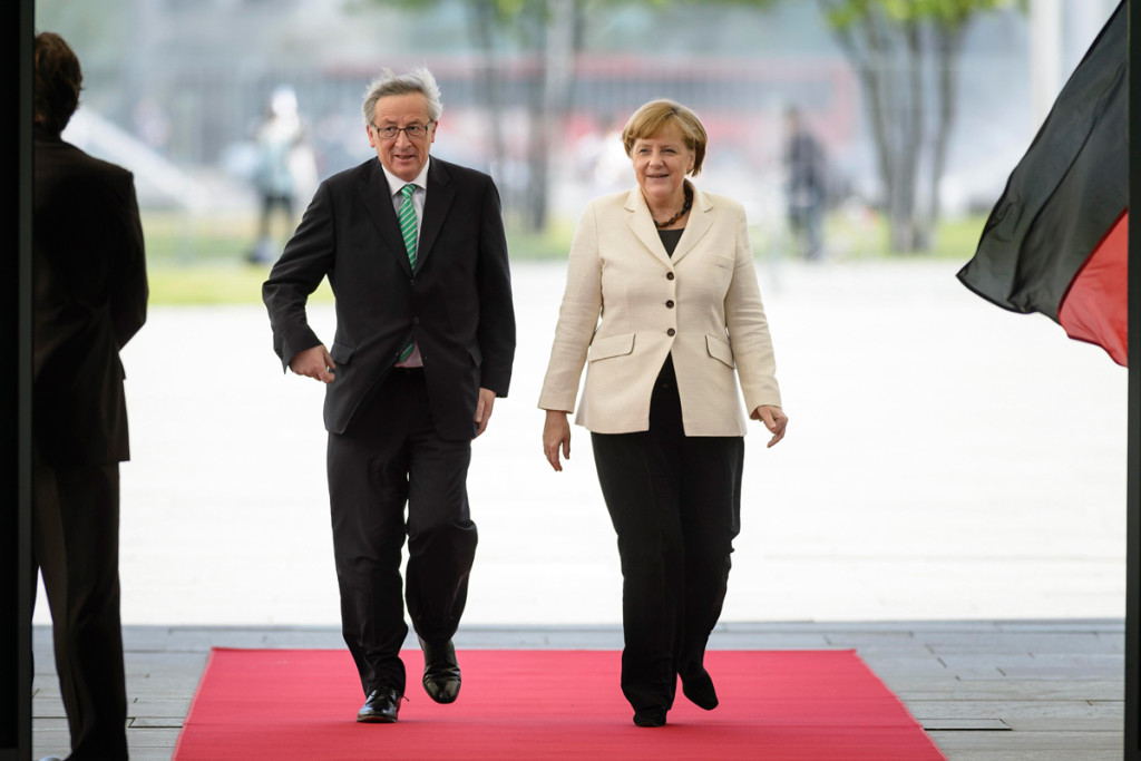 Angela Merkel and Jean-Claude Juncker walk along the red carpet.