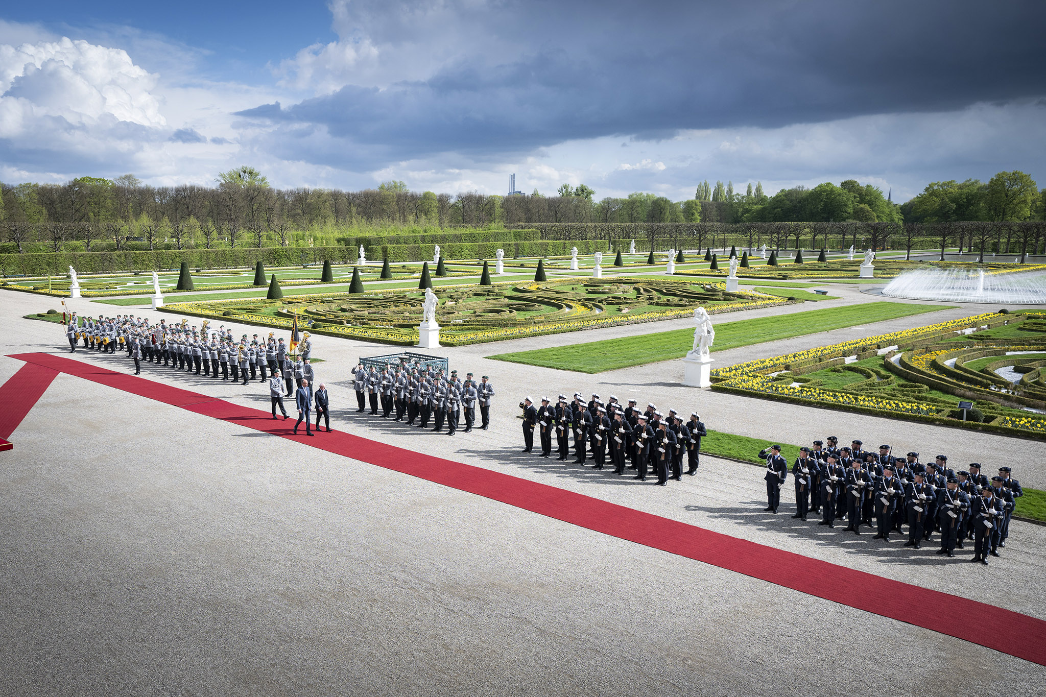 The Federal Chancellor and the Brazilian President inspect the guard of honour of the Bundeswehr on a red carpet. In the background, the palace gardens of Herrenhausen Palace.