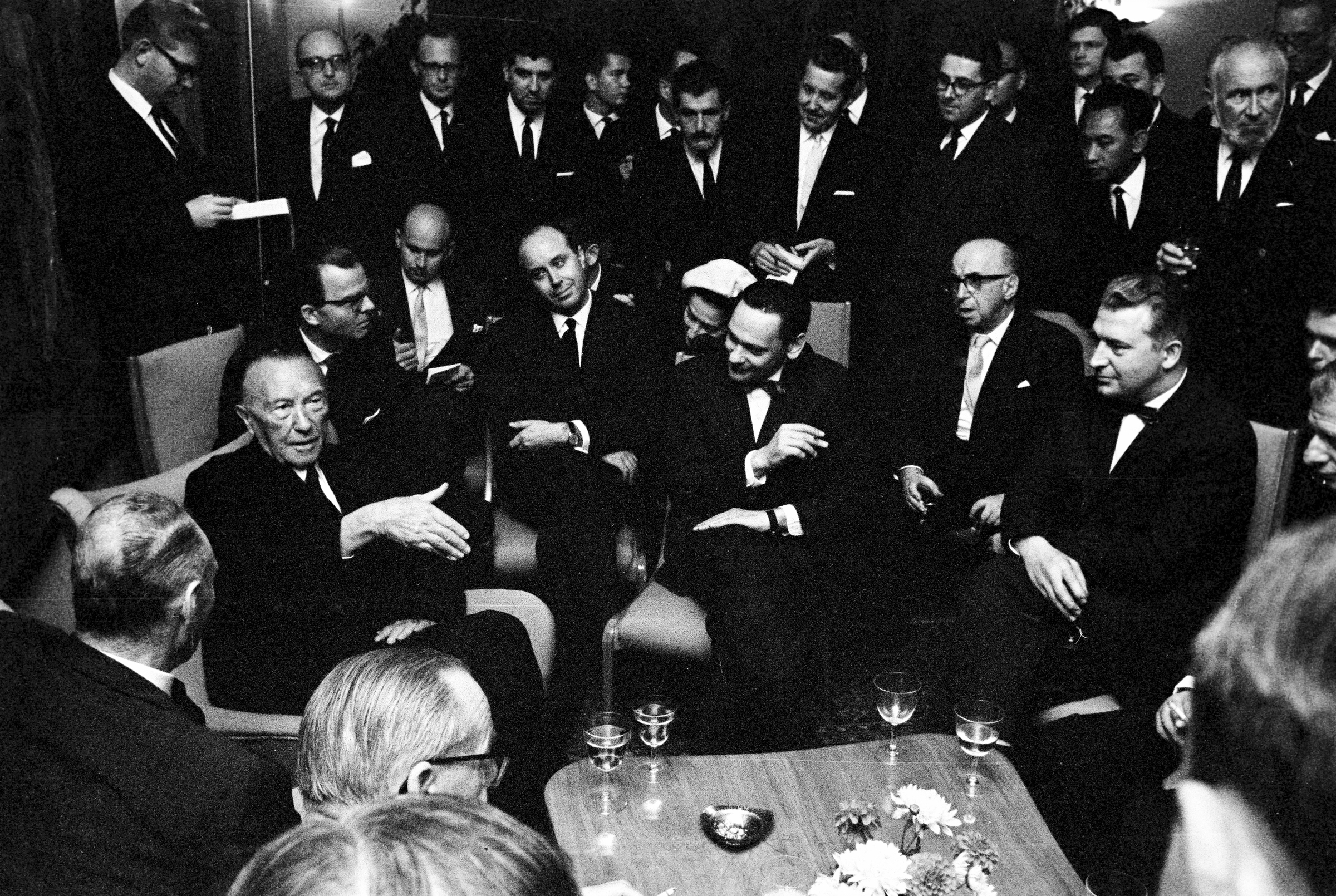 Schwarz-weiß-Fotografie zeigt Bundeskanzler Konrad Adenauer im Gespräch mit Vertretern des Vereins der Auslandspresse.