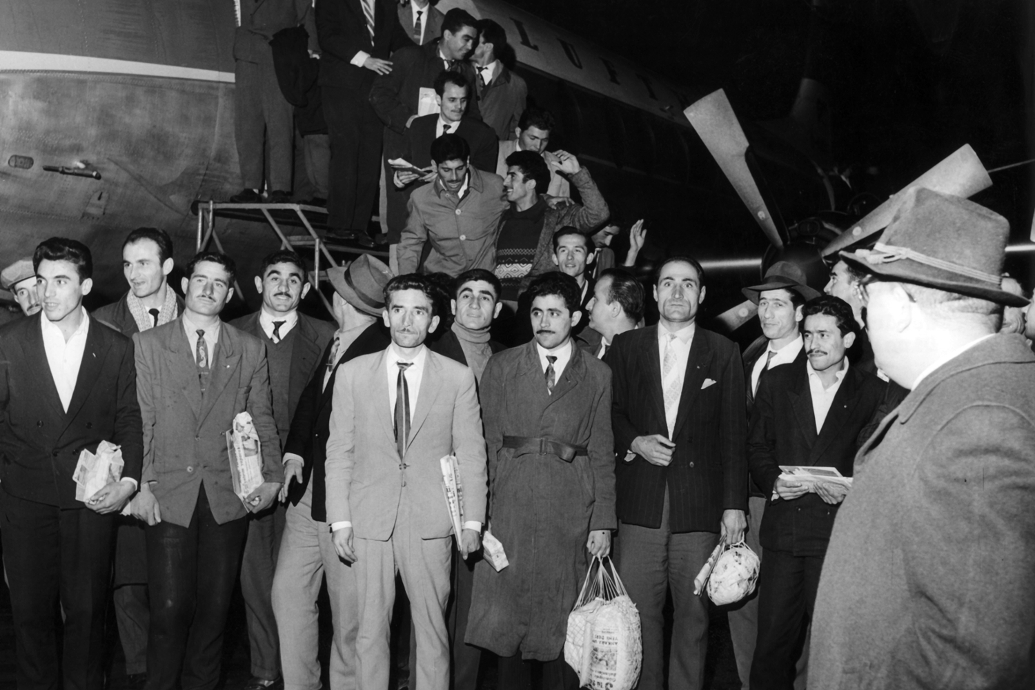 Auf dem Flughafen in Düsseldorf sind türkische Gastarbeiter aus dem Flugzeug gestiegen und stehen auf dem Rollfeld.