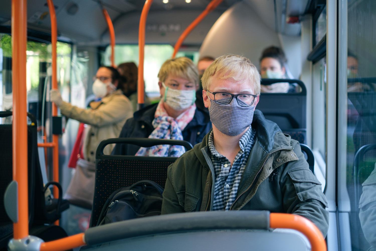 Menschen im Bus tragen einen Mund-Nasen-Schutz.