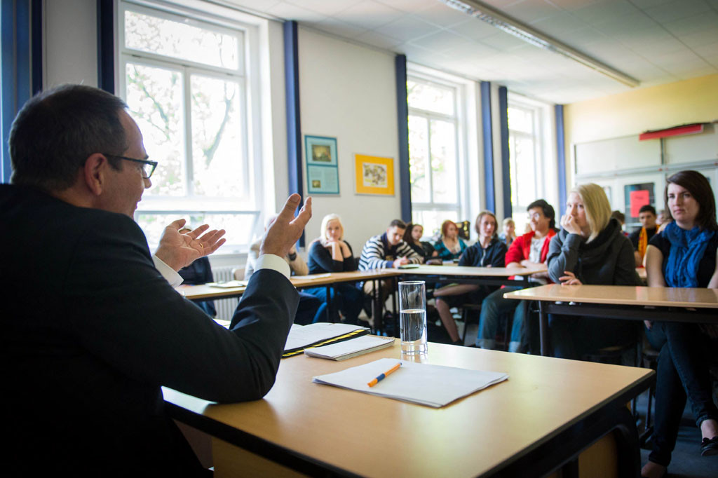 Deputy government spokesman Georg Streiter speaks to school pupils in a classroom.