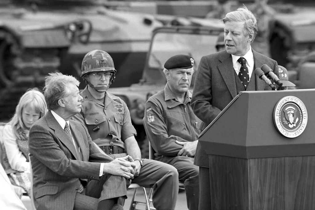 Bundeskanzler Helmut Schmidt (am Rednerpult) und der amerikanische Präsident Jimmy Carter (links, hinter ihm links: seine Tochter Amy Carter) besuchen den US-Stützpunkt Erbenheim, um einer Übung der deutschen und amerikanischen Streitkräfte beizuwohnen.