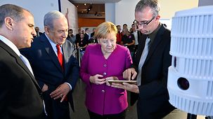 Bundeskanzlerin Angela Merkel und Israels Premierminister Benjamin Netanjahu an einem Informationsstand.