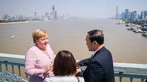 Bundeskanzlerin Angela Merkel unterhält sich auf einer Brücke über den Chang Jian mit dem Provinzgouverneur.