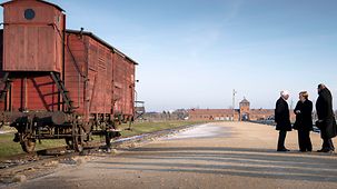 Die Kanzlerin steht neben einem alten Eisenbahnwaggon auf dem Gelände des ehemaligen Konzentrationslagers Auschwitz.