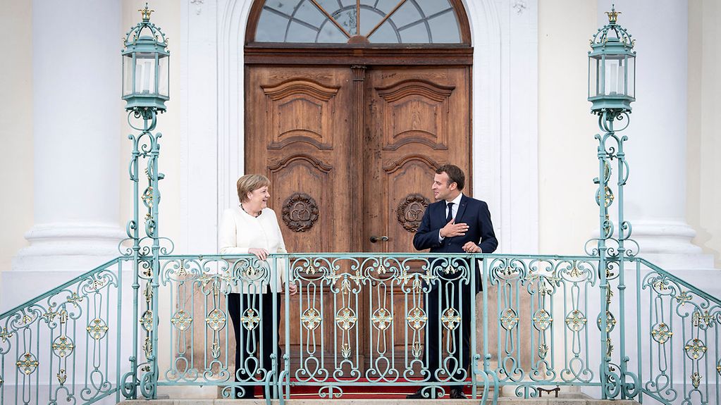 Kanzlerin Merkel und Präsident Macron vor einer Tür.