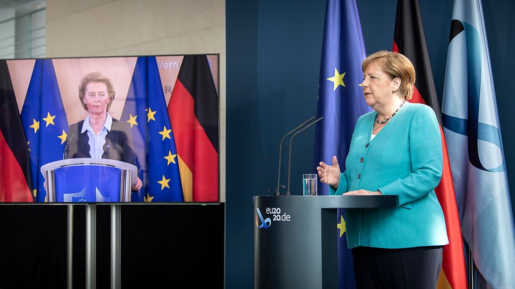 Chancellor Angela Merkel gives a press conference; European Commission President Ursula von der Leyen can be seen on a monitor next to the Chancellor.