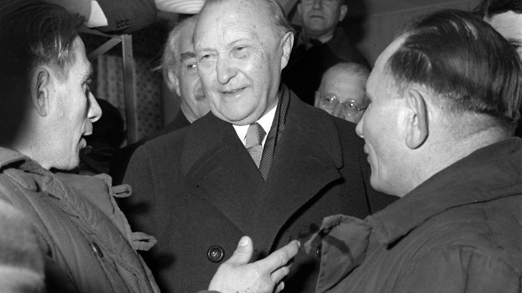 Bundeskanzler Konrad Adenauer (M.) im Gespräch mit Heimkehrern aus sowjetischer Kriegsgefangenschaft im Lager Friedland 1954
