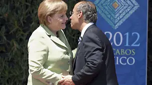 Felipe Calderon welcomes Angela Merkel in front of the G20 logo.