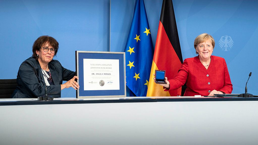 Die Vorsitzende des Bundesverbandes der Ärztinnen und Ärzte des Öffentlichen Gesundheitsdienstes, Ute Teichert, überreicht Kanzlerin Merkel die Johann-Peter-Frank-Medaille.