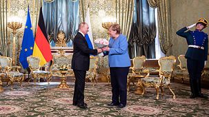 Russian president Vladimir Putin welcomes Federal Chancellor Angela Merkel with flowers.