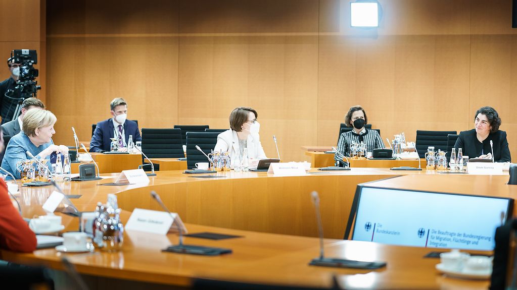 Das Bild zeigt einen Konferenztisch im Kanzleramt, an dem Teilnehmer der Preisverleihung sitzen.