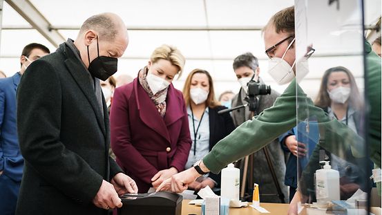 Bundeskanzler Olaf Scholz testet im Ankunftszentrum in Berlin-Tegel die Registrierung mit Fingerabdruck.