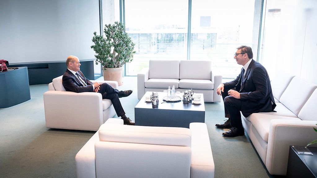 The photo shows Federal Chancellor Scholz and President Vučić. They are seated in white chairs at the Chancellery.