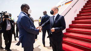Macky Sall, Präsident des Senegal, begrüßt Bundeskanzler Olaf Scholz auf dem Flughafen.