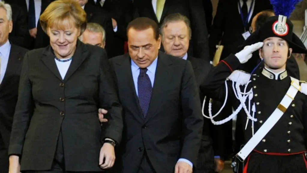 A carabinieri salutes as Chancellor Angela Merkel and Prime Minister Silvio Berlusconi arrive.
