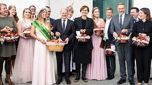 Federal Chancellor Scholz receiving baskets of apples from apple and blossom queens at the Chancellery.