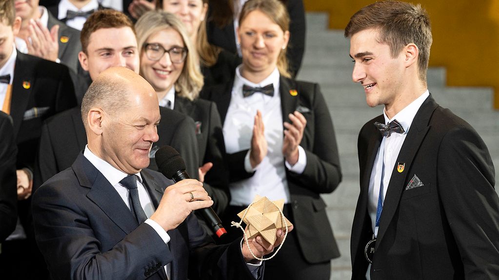 Silbermedaillengewinner Philipp Kaiser überreicht Bundeskanzler Scholz einen aus Holz gefertigten Weihnachtsstern