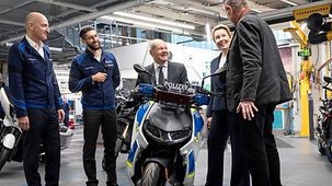 Bundeskanzler Olaf Scholz sitzt auf einem Polizei-Motorrad.