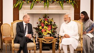 Bundeskanzler Scholz und der indische Premierminister Scholz sitzen Seite an Seite und schauen sich gegenseitig mit freundlichem Lachen an. 