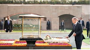 Bundeskanzler Scholz legt am ewigen Feuer der Ghandi-Gedenkstätte „Rajghat“ einen Kranz nieder.