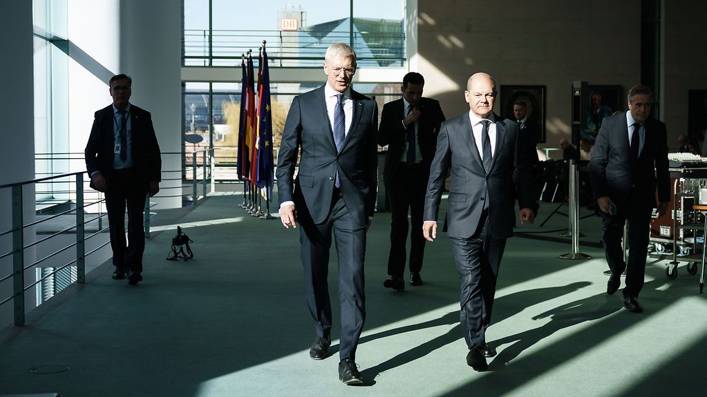 German Chancellor Olaf Scholz walking alongside Latvian Prime Minister Krišjānis Kariņš.