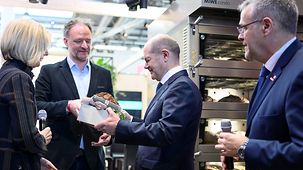 Federal Chancellor Olaf Scholz at the Fickenschers Backhaus GmbH stand during his visit to the International Handicrafts Fair.