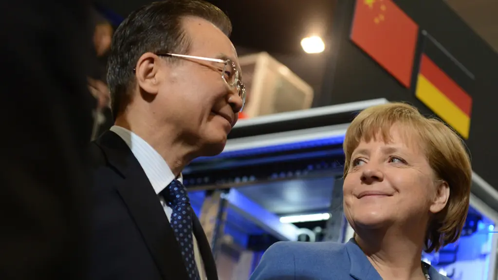 Federal Chancellor Merkel and Premier Wen stand underneath a German and a Chinese flag.