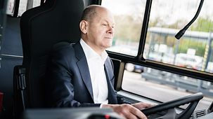 Bundeskanzler Olaf Scholz beim Besuch eines Betriebshof der Berliner Verkehrsbetriebe am Steuer eines E-Busses.