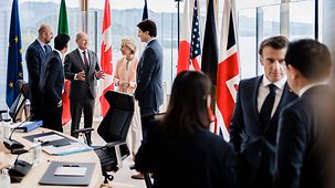Blick in den Sitzungssaal des G7-Gipfels. Die Staats- und Regierungschefs tauschen sich stehend aus, bevor das Programm des zweiten Tages beginnt.