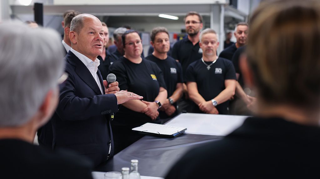 Federal Chancellor Scholz speaking to staff members in a production facility.