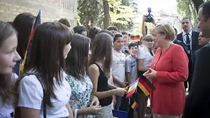 Angela Merkel talks to young people who have gathered to greet her.