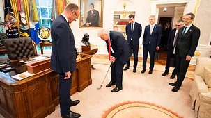 Le président américain Donald Trump tient un club de golf dans ses mains dans le bureau Ovale, en compagnie du chancelier Friedrich Merz.