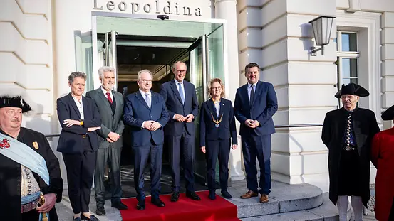 Das Foto zeigt Bundeskanzler Friedrich Merz beim Antrittsbesuch in Sachsen-Anhalt vor der Leopoldina mit Michael Kretschmer, Sachsens Ministerpräsident, und weiteren Personen.