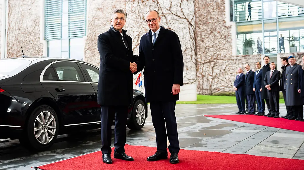 Bundeskanzler Merz begrüßt den kroatischen Ministerpräsidenten Plenković mit einem Handschlag.