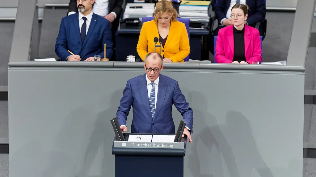 The photo shows Federal Chancellor Merz at the lectern in the German Bundestag.