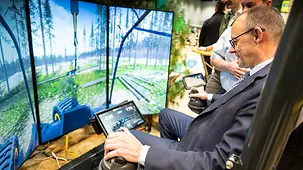 Das Foto zeigt Bundeskanzler Friedrich Merz beim Rundgang über die Grüne Woche in einem Simulator eines Harvesters.