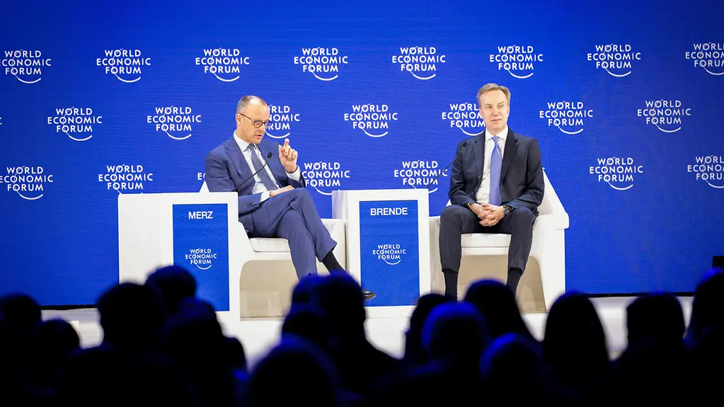 Bundeskanzler Merz und der Vorsitzenden des Weltwirtschaftsforums Børge Brende im Gespräch in Sesseln.