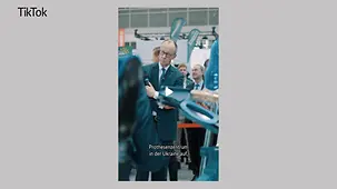 Kanzler Merz mit einem Mikrophon in der Hand auf der Handwerksmesse. Im Hintergrund weitere Personen, im Vordergrund sind medizinische Prothesen zu erkennen.