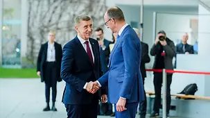Bundeskanzler Friedrich Merz begrüßt Andrej Babiš, Tschechiens Ministerpräsident, mit einem Handschlag. Im Hintergrund verschwommen Fotographen und weitere Personen.