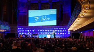 Bundeskanzler Friedrich Merz bei einer Rede auf der Bühne in einer vollen Festhalle. 
