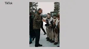 Kanzler Merz trägt eine Tarnjacke und spricht in einer Schneelandschaft mit Soldatinnen und Soldaten in weißer Bekleidung.