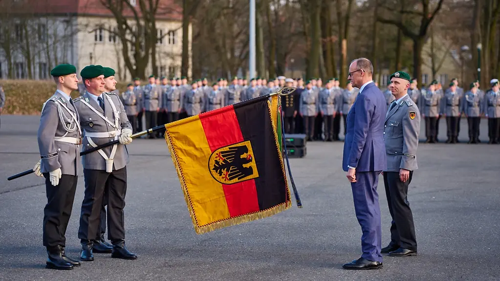 Bundeskanzler Merz mit dem Fahnenband und Soldateb