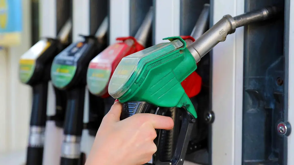 A hand takes a nozzle from the fuel pump