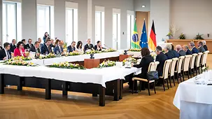 Die Regierungen Deutschlands und Brasiliens sitzen an einem großen Tisch. Im Hintergrund Fotografen und Dolmetscher.
