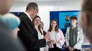 Bundeskanzler Friedrich Merz im Gesrpäch mit Schülerinnen und Schülern.