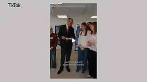 Bundeskanzler Merz im Gespräch mit Schülerinnen in einer Schule.